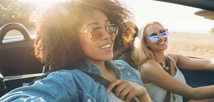 two women driving a convertible car wearing sunglasses