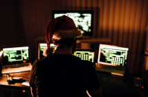 Person with a holiday hat on, behind computers