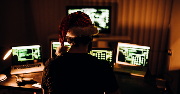 Person with a holiday hat on, behind computers