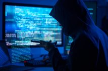 Person in a hoodie on the phone and behind a computer