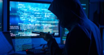 Person in a hoodie on the phone and behind a computer