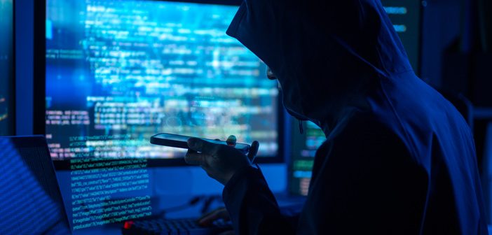 Person in a hoodie on the phone and behind a computer